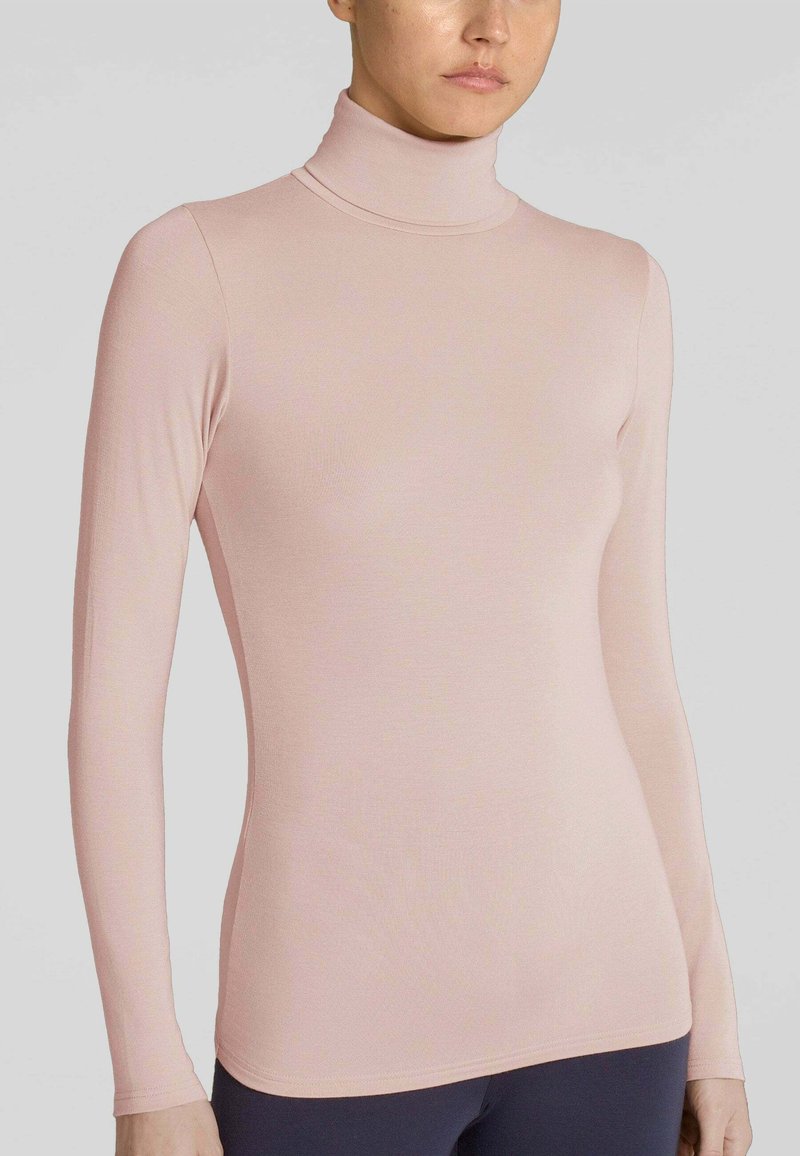 Maglietta a maniche lunghe con collo alto in rosa chiaro, realizzata in un tessuto morbido ed elastico. Presenta una forma aderente e dettagli di cucitura minimi.
