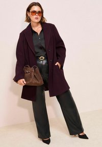 Caban din lână burgundy cu guler mare, purtat peste un bluză din satin negru, pantaloni din faux piele negri, geantă din suede maro și pantofi cu vârf ascuțit negri.