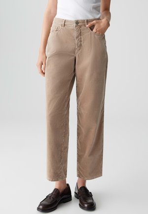 Beige gerade geschnittene Hose mit glatter Textur, vier Taschen und Knopfverschluss, kombiniert mit dunklen Slippern.