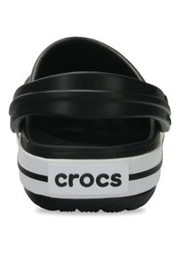 Scarpe slip-on Crocs nere con due cinturini neri, banda bianca e strisce nere, fodera interna testurizzata e logo sul tallone.