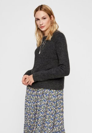 Maglione a maglia grigio scuro con scollo rotondo e maniche lunghe. Abbinato a una gonna a fiori con tonalità blu, verde e beige.