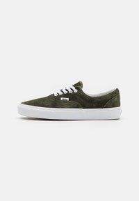 Zapatillas de ante verde con suela de goma blanca. Presenta un diseño clásico de cordones y un cuello acolchado. Etiqueta de logo pequeña en el lado exterior.