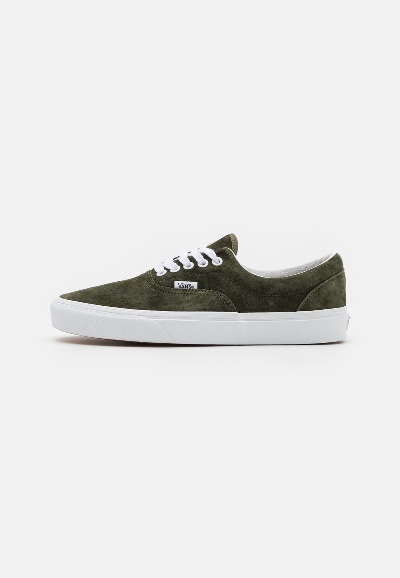 Zapatillas de ante verde con suela de goma blanca. Presenta un diseño clásico de cordones y un cuello acolchado. Etiqueta de logo pequeña en el lado exterior.