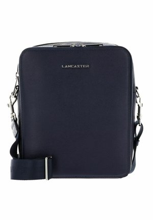 Navy blauwe leren schoudertas met een textuurafwerking, zilveren hardware, een ritsluiting en een verstelbare schouderband, met een logo aan de voorkant.