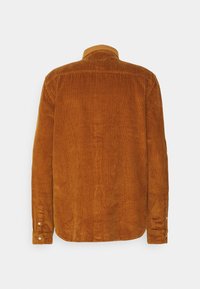 Brun kordflöjlskjorta, strukturerad med vertikala ränder, har krage, långa ärmar och knäppta manschetter. Bakvyn visar en slät finish.