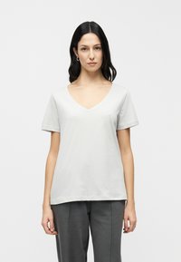 Ανοιχτό γκρι μπλουζάκι με V λαιμόκοψη από απαλό βαμβάκι, με κοντά μανίκια και άνετη εφαρμογή. Απλό σχέδιο χωρίς ορατά μοτίβα ή διακοσμητικά στοιχεία.