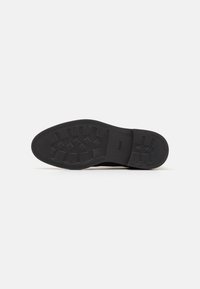 Talpa de pantof negru din cauciuc, cu un model de textură pe tread, margini netede și un logo embossat pe lateral pentru aderență și durabilitate.