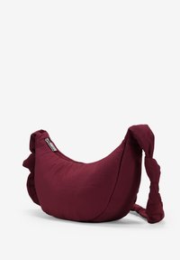 Borsa a spalla in tessuto marrone scuro con una forma morbida e curvata. Presenta manici annodati e una chiusura con zip, che offrono accenti di trama.