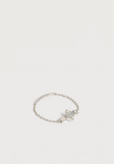 Bracelet chaîne en argent avec un pendentif en cristal en forme d’étoile et une plaque rectangulaire gravée sur fond blanc.