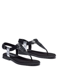 Musta varvassandaali, jossa on litteä pohja, metallinhohtoinen hopeinen yksityiskohta nilkkaremmin kohdalla ja teksturoitu musta pohjallinen.