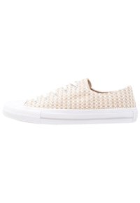 Zapatillas de lona tejida beige con suela de goma blanca, punta redonda, cinco ojales y patrón texturizado en la parte superior. Diseño clásico de corte bajo.