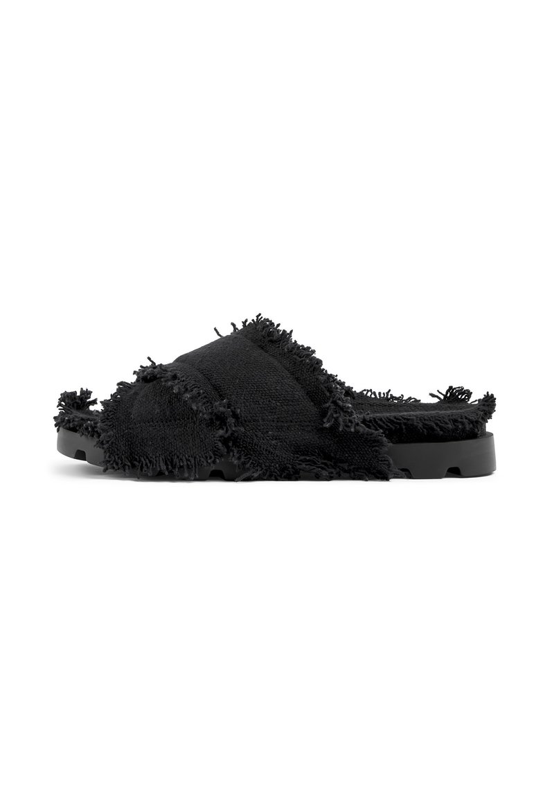 Svarta slidesandaler gjorda av texturerad tyg med en fransad kantdetalj, med en platt svart sula och öppen tådesign.