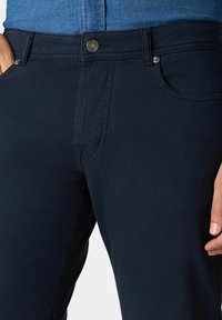 Pantaloni blu navy in misto cotone, con chiusura a bottoni, tasche frontali e una texture liscia e elegante.