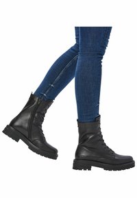 Zwarte leren veterschoenen met zijritsen, robuuste zolen en een gladde afwerking, gedragen met slimfit blauwe jeans.