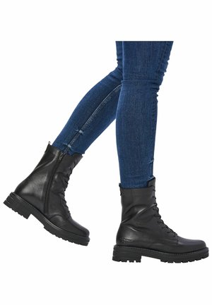 Zwarte leren veterschoenen met zijritsen, robuuste zolen en een gladde afwerking, gedragen met slimfit blauwe jeans.