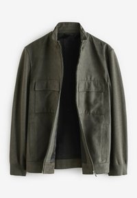 Veste olive avec col montant, dotée d'une fermeture éclair, de deux poches à rabat à l'avant et de panneaux en tissu contrasté sur les manches. Texture lisse.