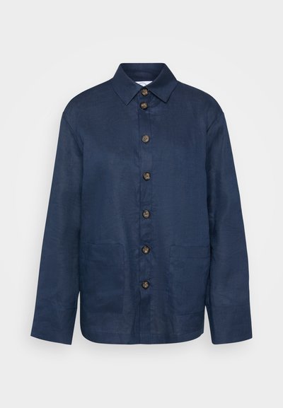 Tumesinine linane särk, millel on kaelus, esistupid ja kaks küljetaskut; kangas on veidi tekstureeritud.