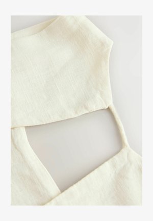 Nahaufnahme eines cremefarbenen, strukturierten Kleidungsstücks aus Stoff mit dünnen Schulterträgern und quadratischem Ausschnitt auf hellem Hintergrund.