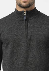 Houtskoolgrijze zip-up trui met een hoge kraag en contrasterende marineblauwe ritssluiting. Gebreide textuur met een getailleerde pasvorm.