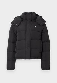Doudoune noire avec col montant, capuche détachable avec boutons-pression, et petit logo "CK" blanc sur la poitrine gauche.