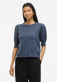 Pull en tricot à manches courtes de couleur bleu foncé, avec un col rond et un design à manches bouffantes, terminé par un ourlet léger.