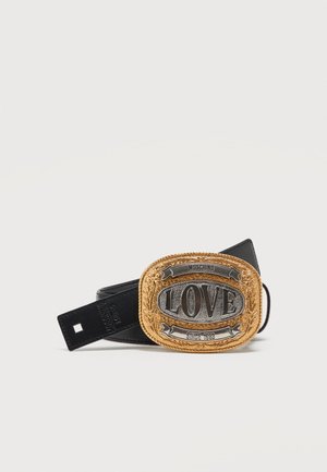 Ceinture en cuir noir avec une grande boucle ornée en or et argent gravée de "LOVE" et "MOSCHINO" sur un fond blanc uni.