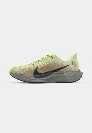 Lys grønne joggesko med et pustende mesh-overdel, grå mellomsåle, svart Nike swoosh og lyse gule detaljer på hælen.