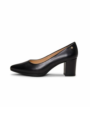 Zapato de tacón medio de cuero negro con punta puntiaguda, tacón cuadrado y pequeño logotipo metálico cerca del cuello del tacón, vista lateral sobre fondo blanco.