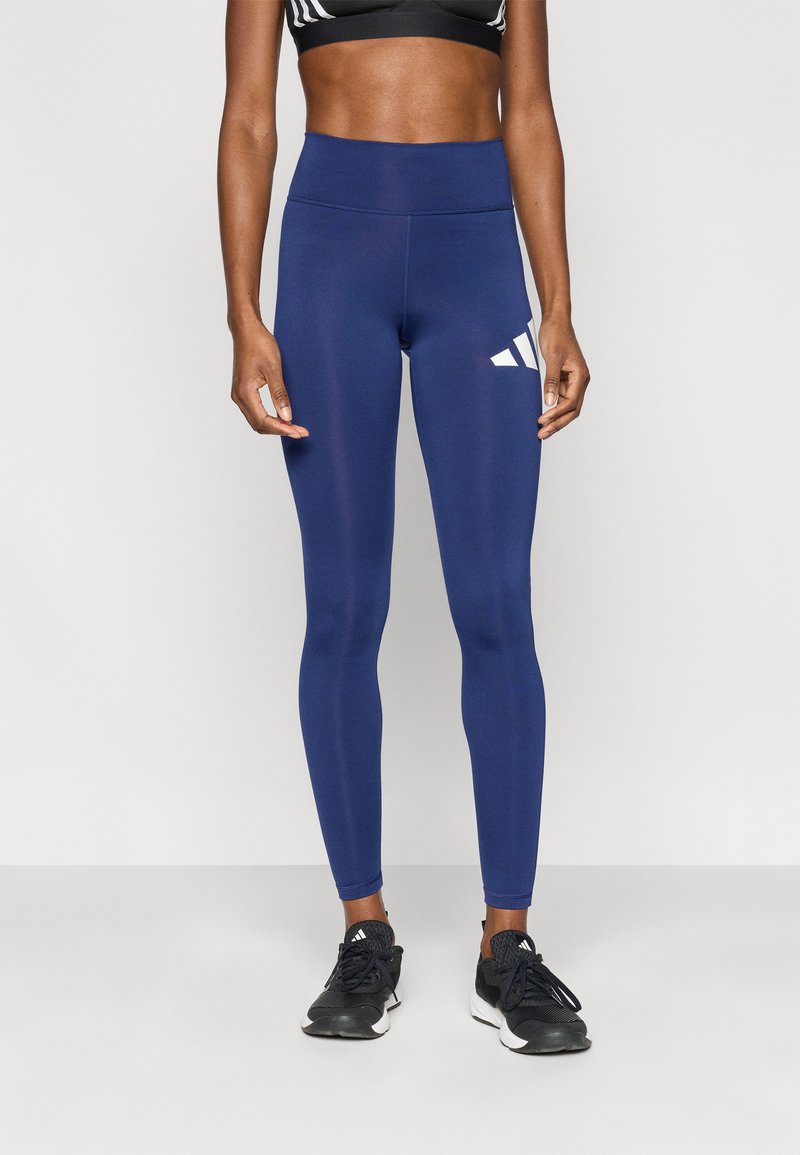 Κολάν σε ναυτικό μπλε χρώμα από ελαστικό ύφασμα, με ψηλή μέση και λευκό λογότυπο Adidas στο αριστερό μηρό. Ομαλή υφή, εφαρμοστό σχέδιο.