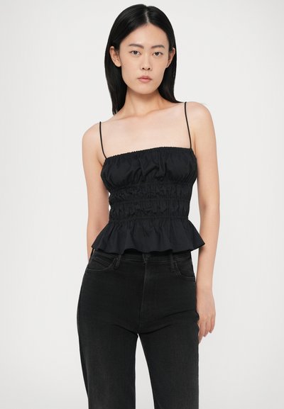 Čierny peplum top z ľahkého materiálu, s naťahovacou korzetovou časťou a tenkými ramienkami, v kombinácii s čiernymi džínsami. Jednofarebný, jednoducho navrhnutý.