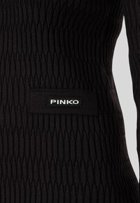 Abito nero lavorato a maglia con un motivo testurizzato a righe verticali. Patch con il logo PINKO sulla parte frontale. Design a maniche lunghe.