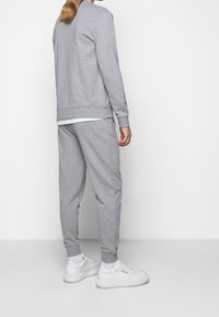 Sudadera gris y joggers a juego hechos de tela suave, con puños y cintura acanalados, complementados con zapatillas blancas.