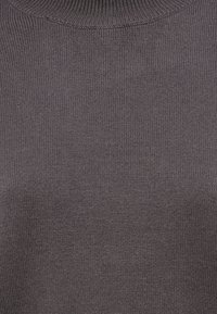 Σκούρο γκρι πλεκτό πουλόβερ με ψηλό λαιμό. Διαθέτει λεία υφή και ριμπ λεπτομέρειες κατά μήκος του γιακά και των μανσετών.