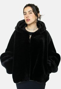 Veste à capuche en fausse fourrure noire avec de longues manches bouffantes et fermeture éclair à l'avant ; texture douce et design minimaliste.