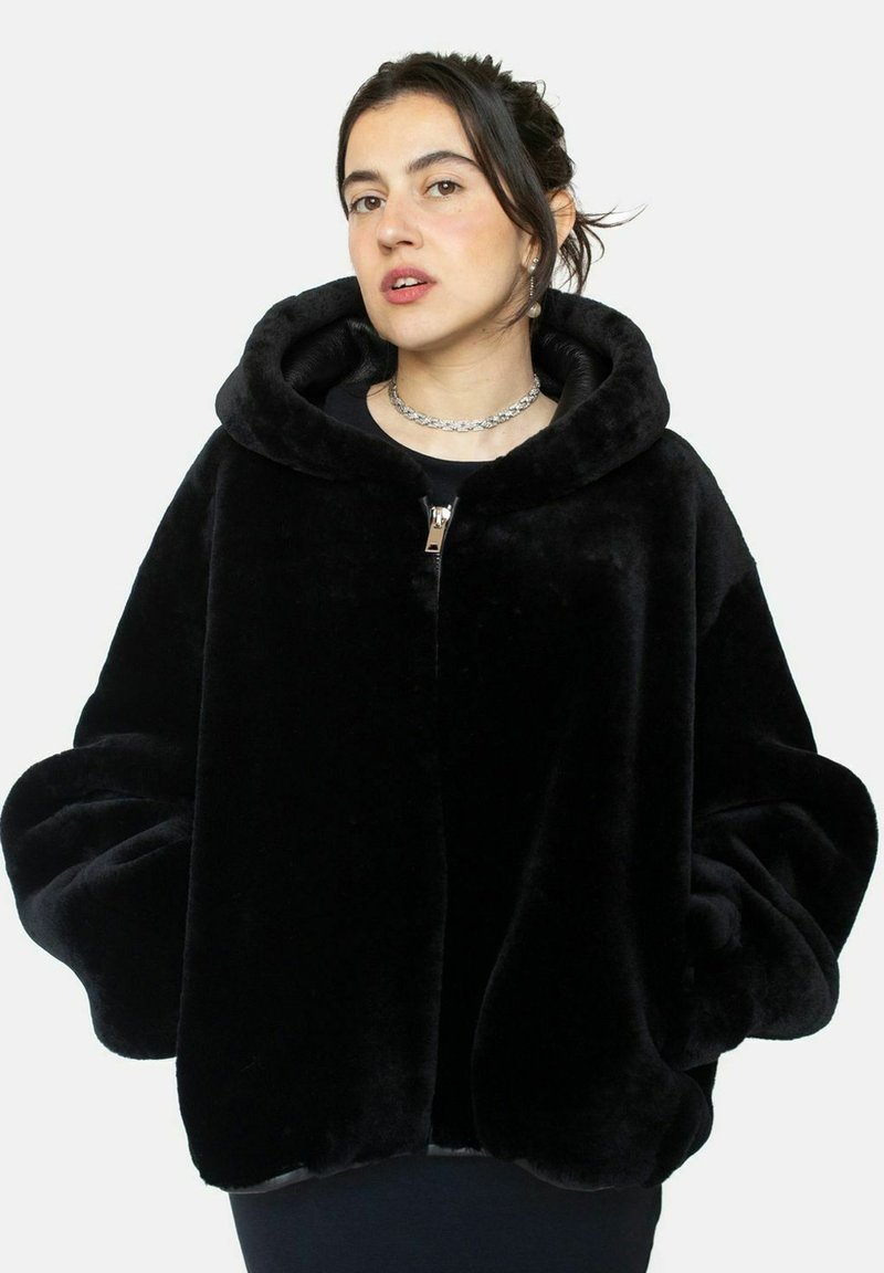 Veste à capuche en fausse fourrure noire avec de longues manches bouffantes et fermeture éclair à l'avant ; texture douce et design minimaliste.