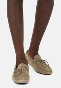 Svetlo béžové semišové loafers so �štruktúrovaným povrchom, s mašľou ako dekoráciou a zaoblenou špičkou. Gumová podrážka s malými výčnelkami pre lepšiu trakciu.