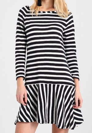 Robe noire et blanche à rayures, à manches longues, avec un corsage droit et une jupe évasée. Rayures verticales sur la partie inférieure.