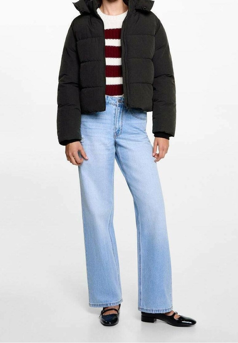 Personne portant une doudoune noire, un pull rayé rouge et blanc, un jean large bleu clair et des chaussures Mary Jane noires.