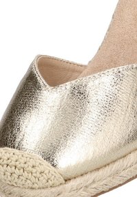 Espadrille metálico dorado con un acabado texturizado, punta redondeada y una suela de yute trenzado para un contraste adicional.