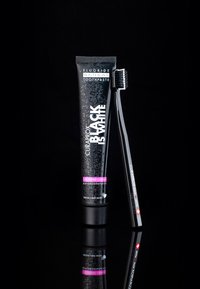 Curaprox Black is White tandkräm i en flaska, svart med silverprickar, har rosa detaljer. Inkluderar en svart tandborste med mjuka borst.