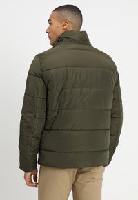 Olivenfarvet pufferjakke med høj krave, quiltet design og elastiske ærmer, der har en glat, syntetisk overflade.