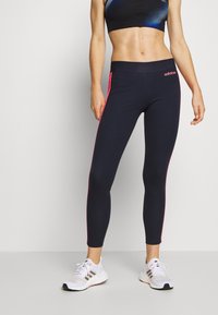 Marina atletiska leggings med rosa sidremsor, med en figurnära design och stretchigt tyg för komfort. Matchas med vita löparskor.