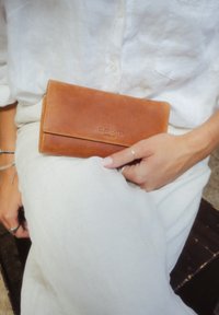 Braune Lederbrieftasche mit glatter Textur und sauberer Naht, ausgestattet mit einem geprägten Logo "HOLZRICHTER BERLIN" auf der Vorderseite.