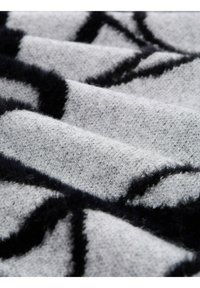 Tissu gris à la texture douce comportant un motif abstrait noir ; montre des plis et de la profondeur dans la surface tissée du tissu.