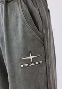 Grijze katoenen joggers met zijzakken, geribbelde tailleband en het PXP-logo in het wit geborduurd op de dij. Zacht, textuurmateriaal.
