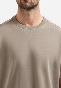 Lichtgrijs T-shirt met korte mouwen, gemaakt van zachte materiaal, met een ronde hals en schone naden, voorzien van een gladde textuur en een minimalistisch ontwerp.