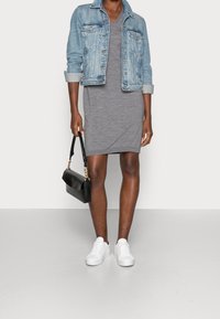 Veste en denim, robe grise, baskets blanches, sac à main noir avec chaîne. Mettez l'accent sur la coupe décontractée, la texture douce et le design casual.