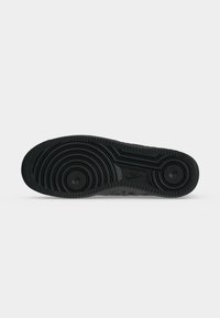 Μαύρη σόλα παπουτσιού Nike με κυκλικά ανάγλυφα σχέδια και το λογότυπο της Nike ορατό στο κεντρικό τμήμα της σόλας.