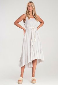 Gestreiftes Midi-Kleid aus leichtem Stoff mit gestuftem Saum, ausgestattet mit einem Gürtel mit Quasten. Sandalen mit Plateau in natürlichen Farben vervollständigen den Look.