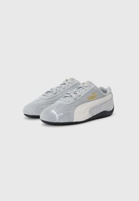 Baskets en suede gris avec un panneau latéral blanc et une semelle extérieure en caoutchouc noir. Comprend des lacets, un logo doré, et des accents blancs sur le talon et sur le côté.
